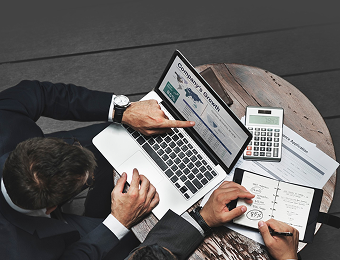 Personen arbeiten am Schreibtisch mit Laptop